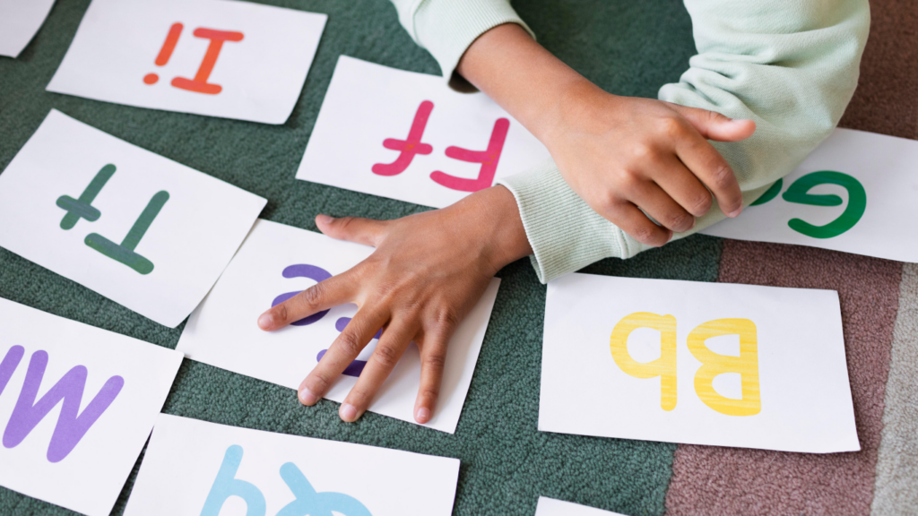 Criança brincando com letras embaralhadas na mesa, para falar sobre a troca de letras na fala