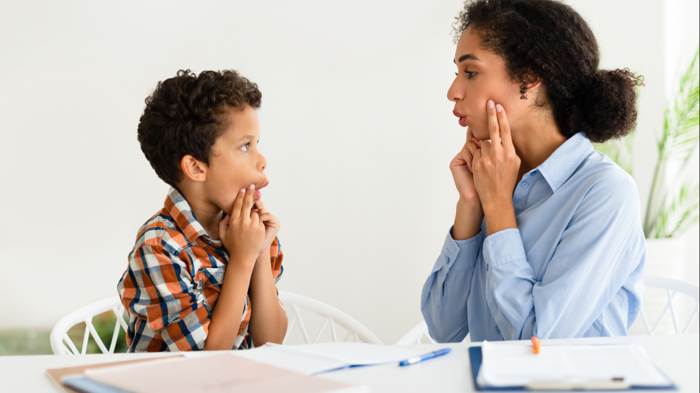 Fonoaudióloga fazendo exercícios vocais com menino, para falar sobre a gagueira infantil