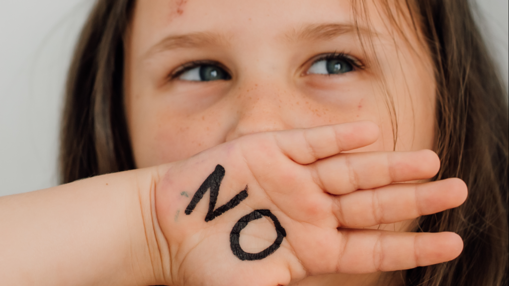 Menina com a mão na boca, para falar sobre a criança que entende mas não fala